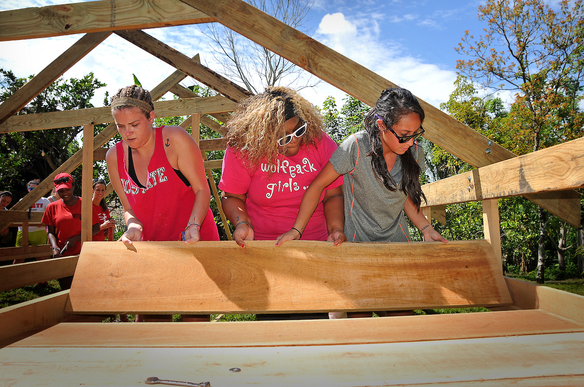 three students place boards for the racks in the cacao drying shed on a trip to Belize in 2025.