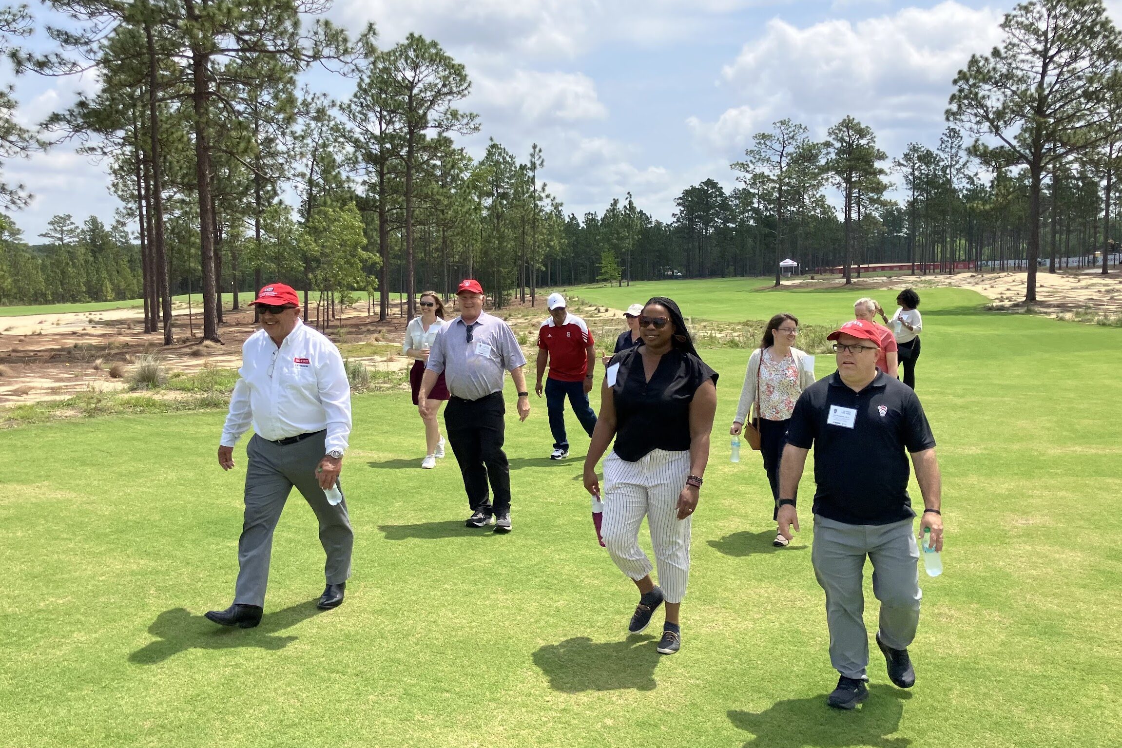 A group of people walking across a golf course