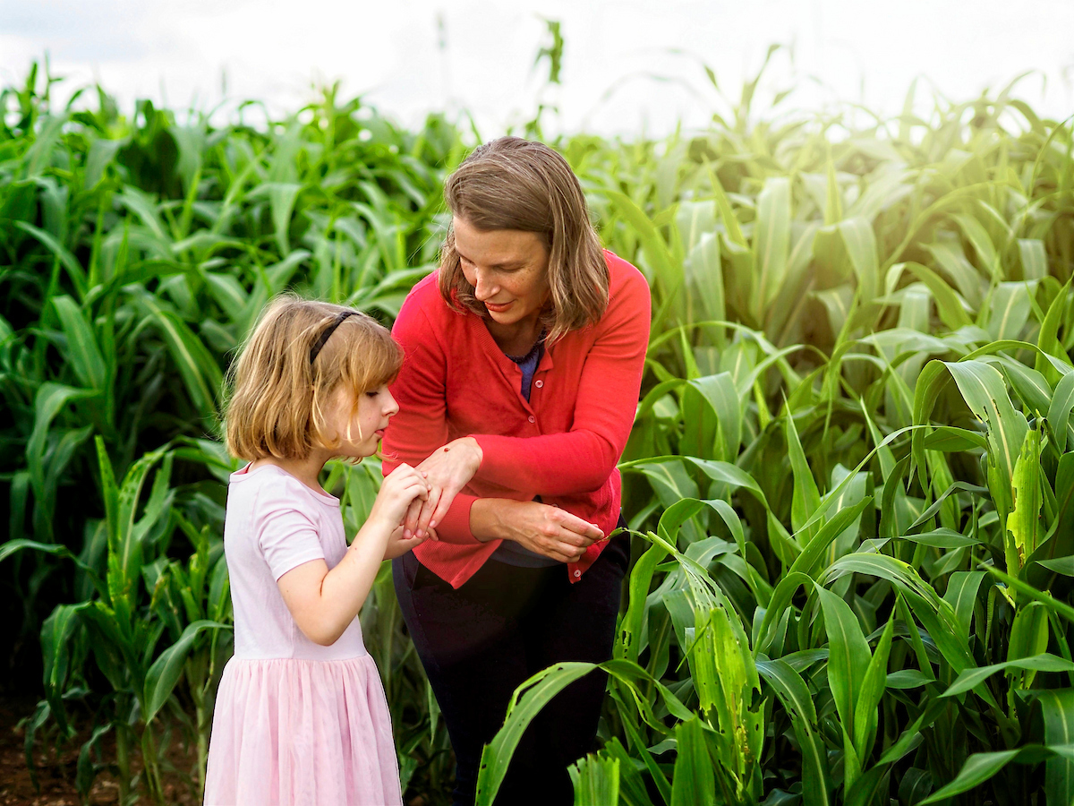 Professor and Extension specialist in Entomology and plant pathology, Hannah Burrack and a young child examine a small bug they found in a corn field at the Lake Wheeler farm.
